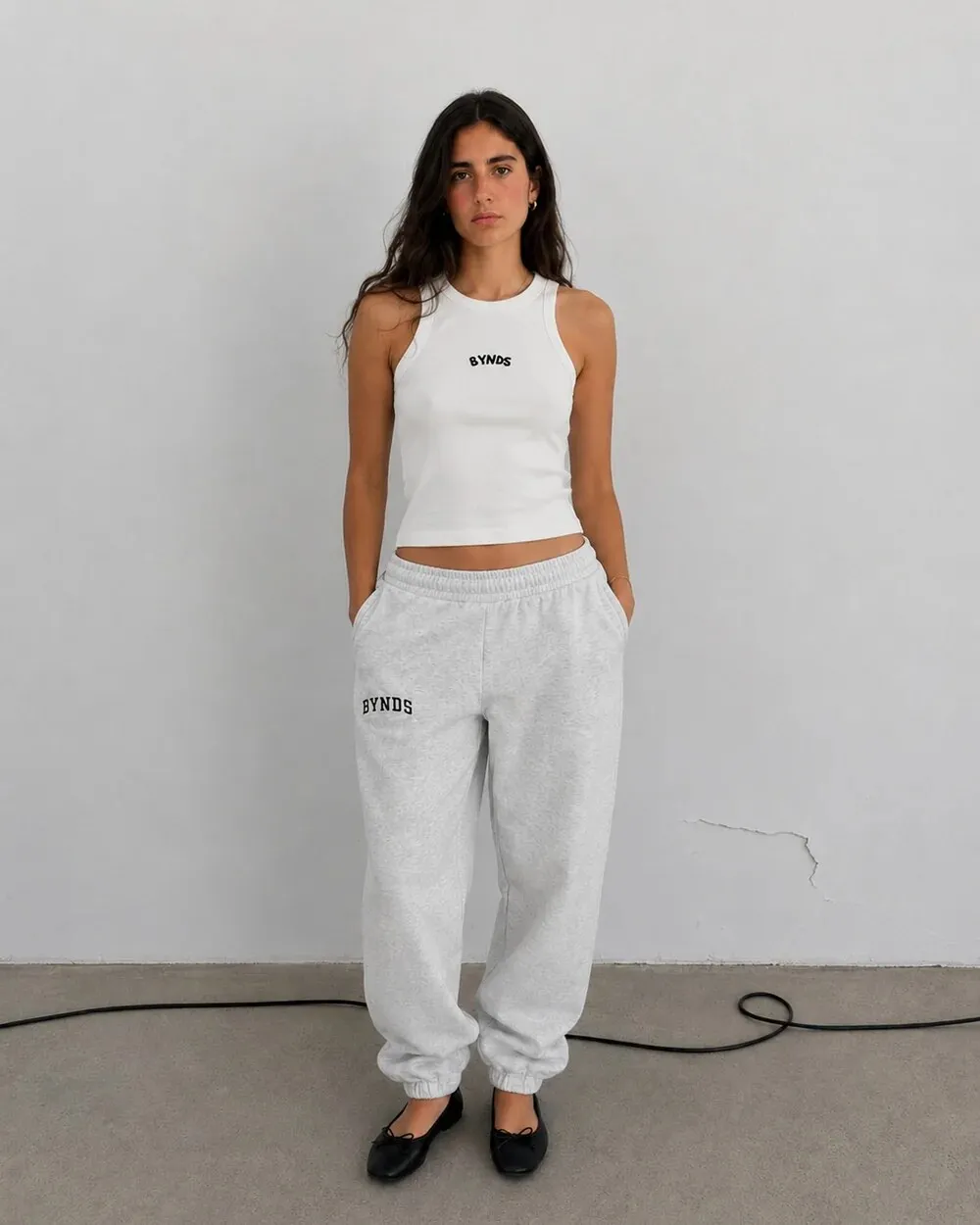 Woman in a white BYNDS tank top and gray BYNDS joggers