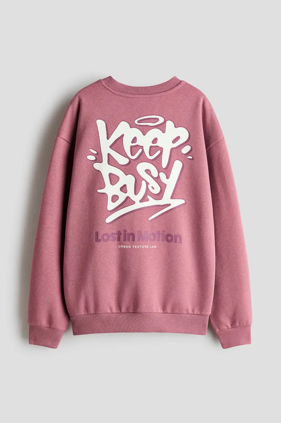 Back of a dusty pink sweatshirt with a large “Keep Busy” graffiti print, for H&M