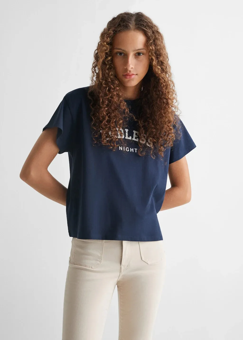 Model in a navy T-shirt with a white varsity print and cream jeans, for Mango