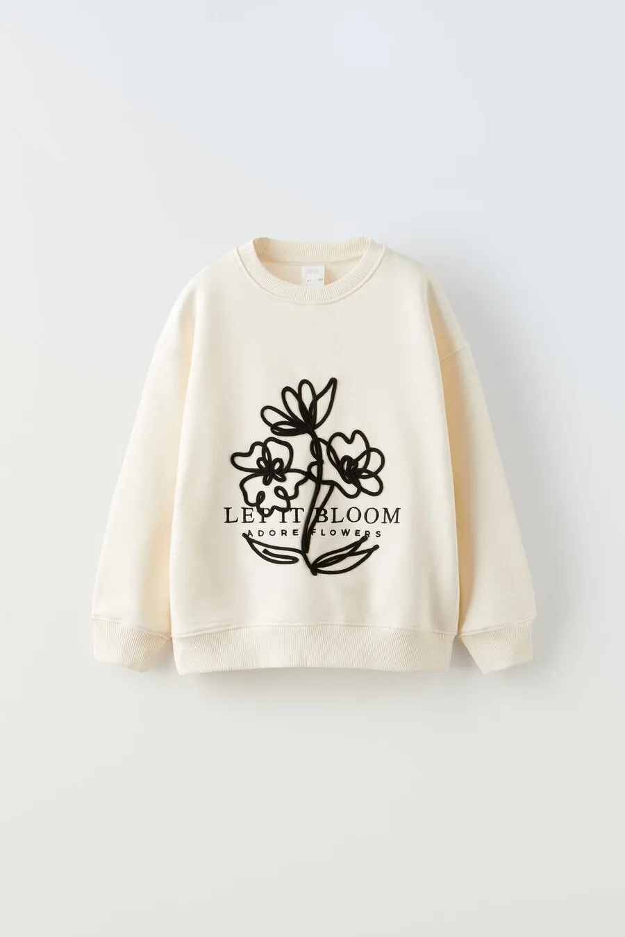 Cream sweatshirt with a black flower drawing and “Let it bloom” lettering, for Zara